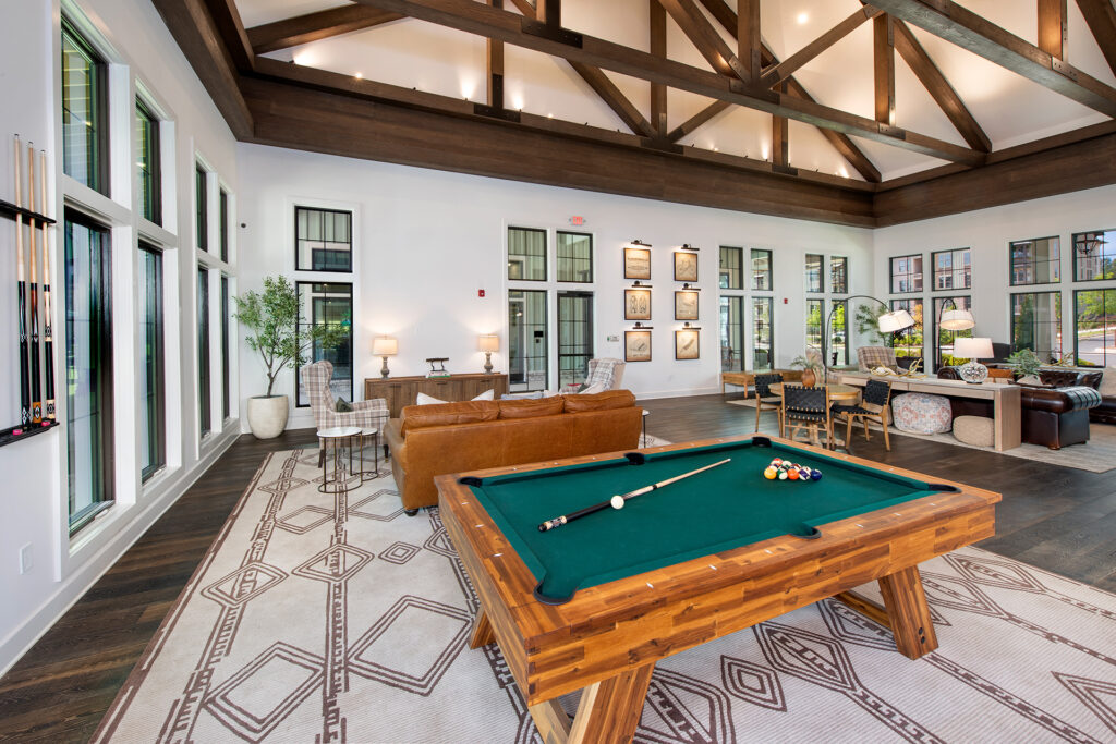 Clubroom lounge with a billiards table, leather seating, and vaulted wood-beam ceiling at Town Kennesaw apartments in Kennesaw, GA