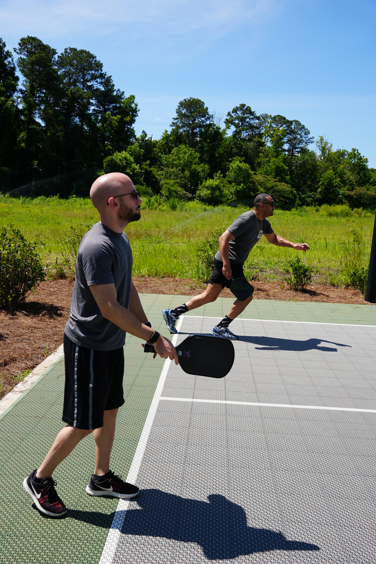 Two residents playing pickleball on the outdoor court at Town Kennesaw luxury apartments in Kennesaw, GA